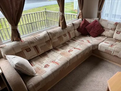 a couch sitting in front of a large window at Clarach Bay Escape 3 Bedroom PetFriendly Caravan with Decking Sleeps 6 in Aberystwyth
