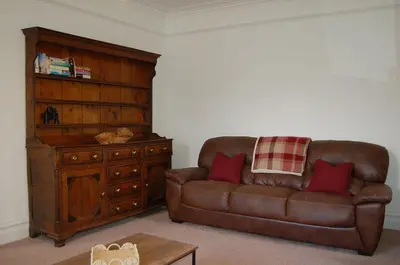 a living room with a leather couch and a dresser at Fegla Fawr - Rustic, rural farmhouse near Barmouth in Arthog