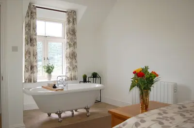 a bathroom with a tub and a window and a vase of flowers at Fegla Fawr - Rustic, rural farmhouse near Barmouth in Arthog
