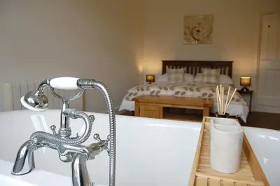 a bathroom with a bath tub and a bedroom at Fegla Fawr - Rustic, rural farmhouse near Barmouth in Arthog