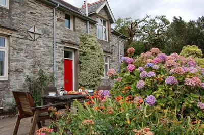a garden with a table and flowers in front of a house at Fegla Fawr - Rustic, rural farmhouse near Barmouth in Arthog