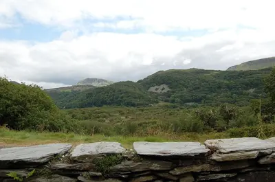 a stone wall with mountains in the background at Fegla Fawr - Rustic, rural farmhouse near Barmouth in Arthog
