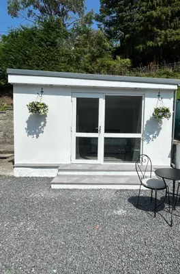 a white garage with two windows and a table and chairs at Forest View Annexe in Ponterwyd