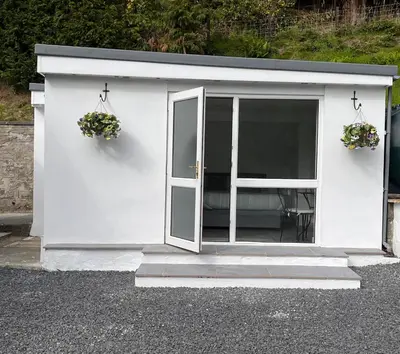a white shed with two potted plants in it at Forest View Annexe in Ponterwyd
