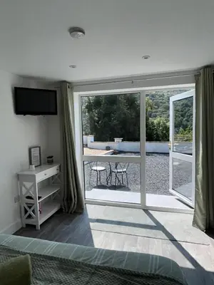 a bedroom with a sliding glass door with a view of a patio at Forest View Annexe in Ponterwyd