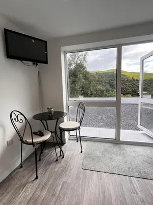 a room with a table and chairs and a large window at Forest View Annexe in Ponterwyd