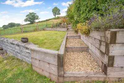 a garden with a retaining wall and some grass at 2 Bed in Defynnog oc-t32724 in Sennybridge