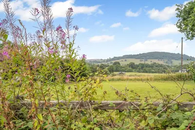 a field with a fence and flowers in the foreground at 2 Bed in Defynnog oc-t32724 in Sennybridge