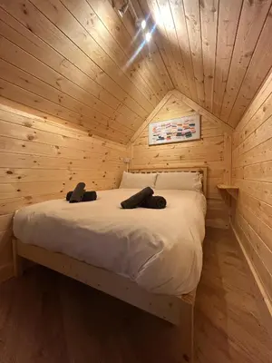 a bed in a wooden room in a cabin at Clogau Tree House Hot tub &sauna in Penmaenpool