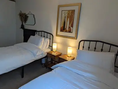 two beds in a bedroom with two lamps on tables at Compton House, Llanfyllin in Llanfyllin