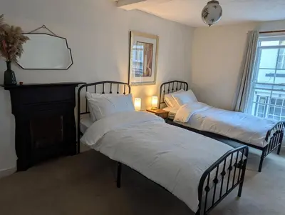 a bedroom with two beds and a fireplace and a window at Compton House, Llanfyllin in Llanfyllin