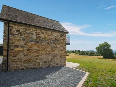 a brick building with a walkway next to a field at Shropshire Way Stay in Farden
