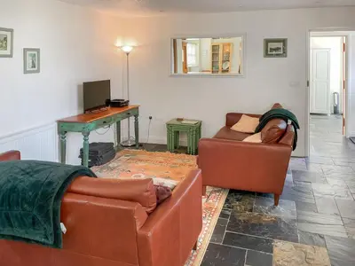 a living room with two leather couches and a table at Caeley Barn in Penybont