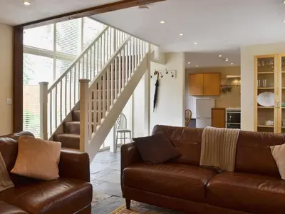 a living room with a couch and a staircase at Caeley Barn in Penybont