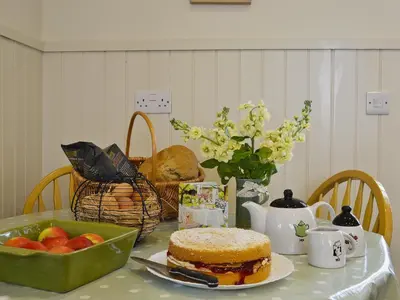 a table with a cake and a basket of fruit at Caeley Barn in Penybont