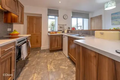 a large kitchen with wooden cabinets and a sink at Bodelen in Llanbedr