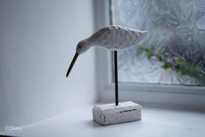 a paper bird on a stand in front of a window at Bodelen in Llanbedr