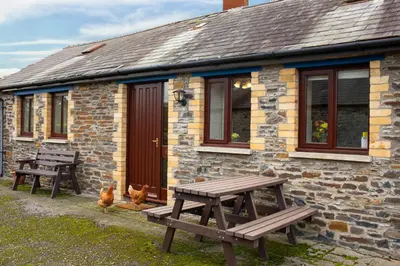 a stone building with two picnic tables in front of it at The Granary Aberystwyth in Aberystwyth