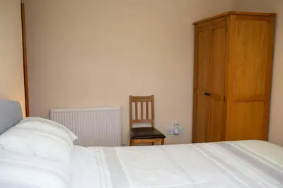 a bedroom with a bed and a wooden cabinet and a chair at The Stable Aberystwyth in Aberystwyth