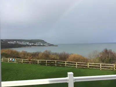 a white fence with a view of a body of water at Lodge - Sleeps 4 Near beach & Free parking in Llanina