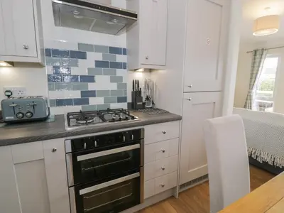 a kitchen with white cabinets and a stove top oven at Platinum Lodge 503 in Talybont