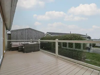 a deck with a couch and chairs on a balcony at Platinum Lodge 503 in Talybont