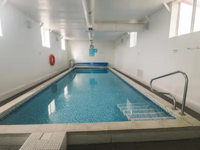 an indoor swimming pool with blue water in a building at Gold Caravan 316 in Talybont