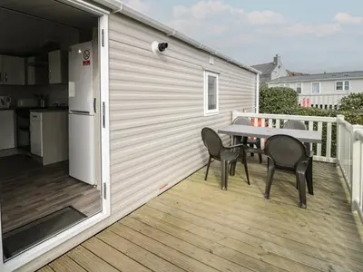 a patio with a table and chairs on a deck at Gold Caravan 316 in Talybont