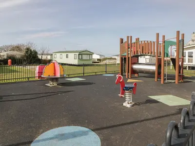a playground with two play equipment in a park at Gold Lodge 201 in Talybont