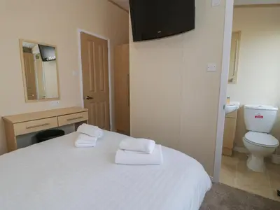 a bedroom with a white bed and a toilet at Gold Lodge 201 in Talybont