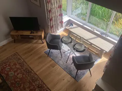 a living room with a table and chairs and a television at The Studio, spacious riverside property in Ludlow with private parking in Ludlow