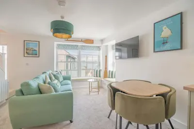 a living room with a blue couch and a table at Mermaid's Apartment by Ty Annie Holidays in New Quay