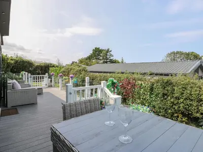 a wooden table with two wine glasses on a deck at Coogee View in New Quay