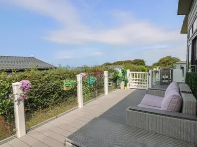 a porch with a couch and a fence at Coogee View in New Quay