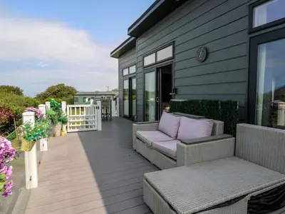 a patio with a couch and chairs on a house at Coogee View in New Quay