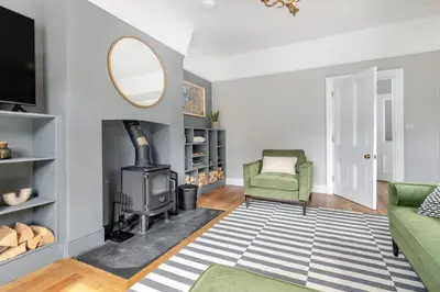 a living room with a fireplace and a green chair at 3 Bed in Cyfronydd oc-e32742 in Llanfair Caereinion
