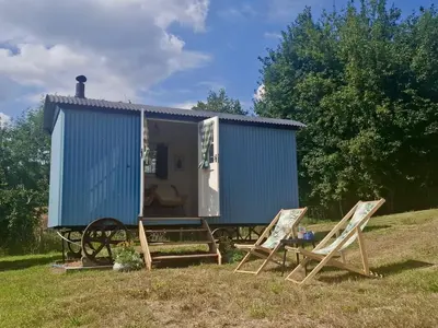 a blue tiny house with two chairs and a table at Tower Farm Holidays - Shepherd's Huts in Llangollen