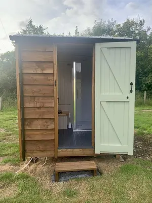 a small shed with a door and a gate at Tower Farm Holidays - Shepherd's Huts in Llangollen