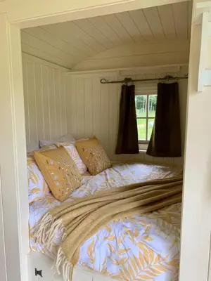a bed in a small room with a window at Tower Farm Holidays - Shepherd's Huts in Llangollen