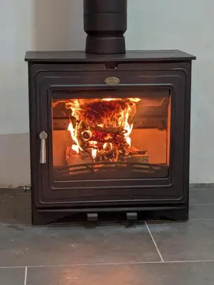 a stove with a fire inside of it at Ty Isaf Welsh Farmhouse with Sea Views in Llanddwywe
