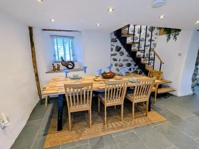 a dining room with a wooden table and chairs at Ty Isaf Welsh Farmhouse with Sea Views in Llanddwywe