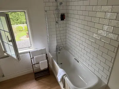 a white bathroom with a tub and a window at 2 Aqueduct Cottages in Wrexham