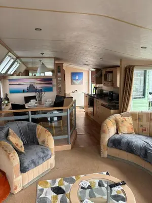 a living room with two couches and a kitchen at Beach Retreat in Ynys-lâs Station