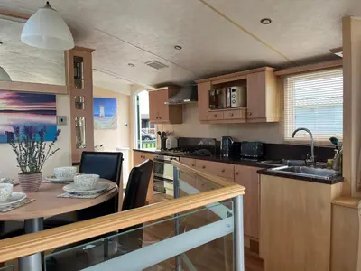 a kitchen with wooden cabinets and a table and a sink at Beach Retreat in Ynys-lâs Station