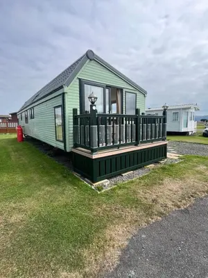 a green house with a porch and a balcony at Beach Retreat in Ynys-lâs Station