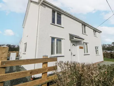 a white house with a wooden fence at Glandwr House in Llandrindod Wells