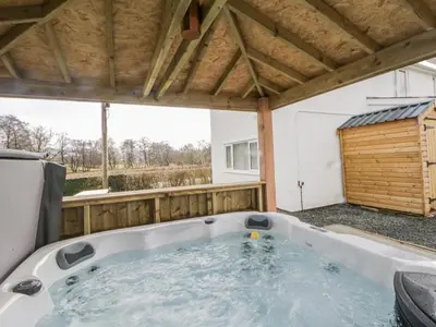 a jacuzzi tub in the backyard of a house at Glandwr House in Llandrindod Wells