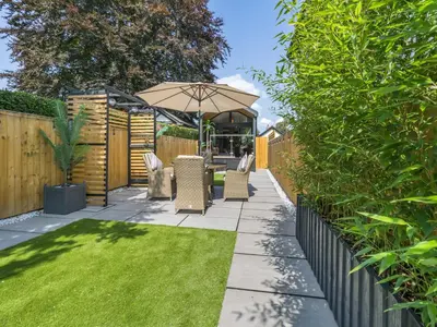 a garden with a patio with an umbrella and grass at Aqueduct Hideaway in Llangollen