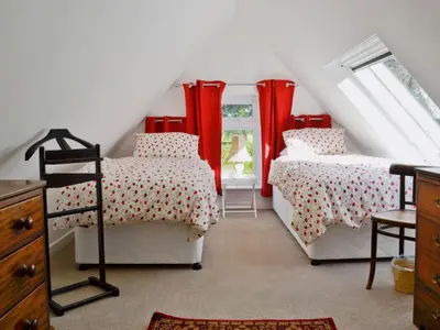 two beds in a attic room with red curtains at Sisial y Llyn in Bala