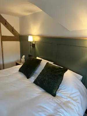 a white bed with two black pillows on it at The Swan in Munslow